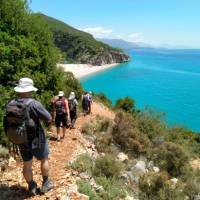 Hikers descending a coastal trail to a beautiful beach in Albania