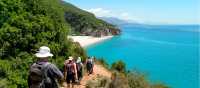 Hikers descending a coastal trail to a beautiful beach in Albania