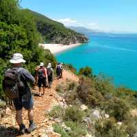 Hikers descending a coastal trail to a beautiful beach in Albania