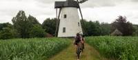 Friends cycling past one of Belgium's stunning windmills.