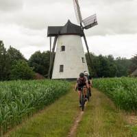 Friends cycling past one of Belgium's stunning windmills.