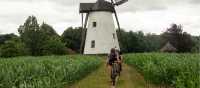 Friends cycling past one of Belgium's stunning windmills.