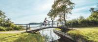 Woman cycling on a scenic wooden bridge in Denmark. | Daniel Villadsen