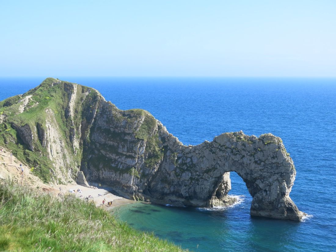 South West Coast Path walkers pass a natural rock arch and cliffs above the sea |  Peter Wells