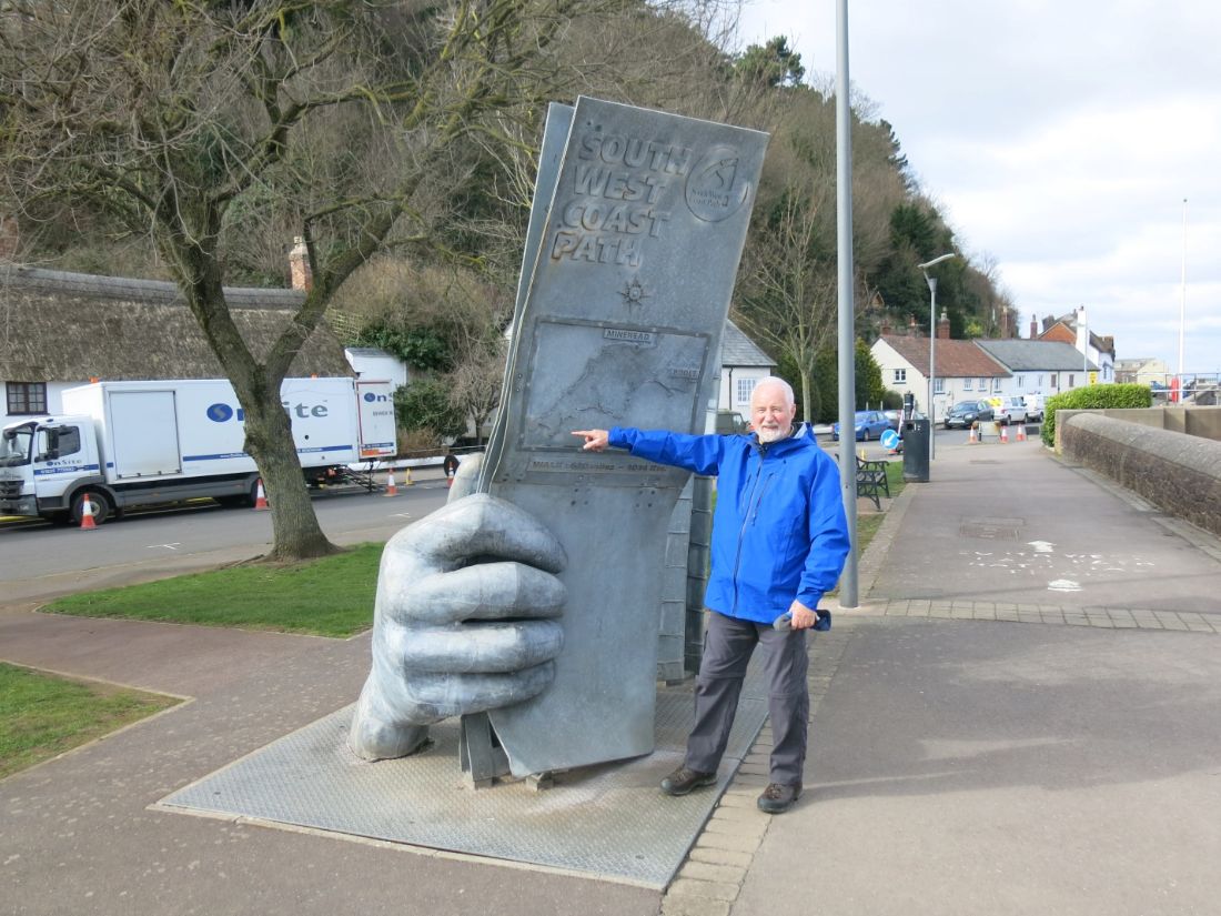 South West Coast Path walker pointing to a giant trail marker sculpture |  Peter Wells