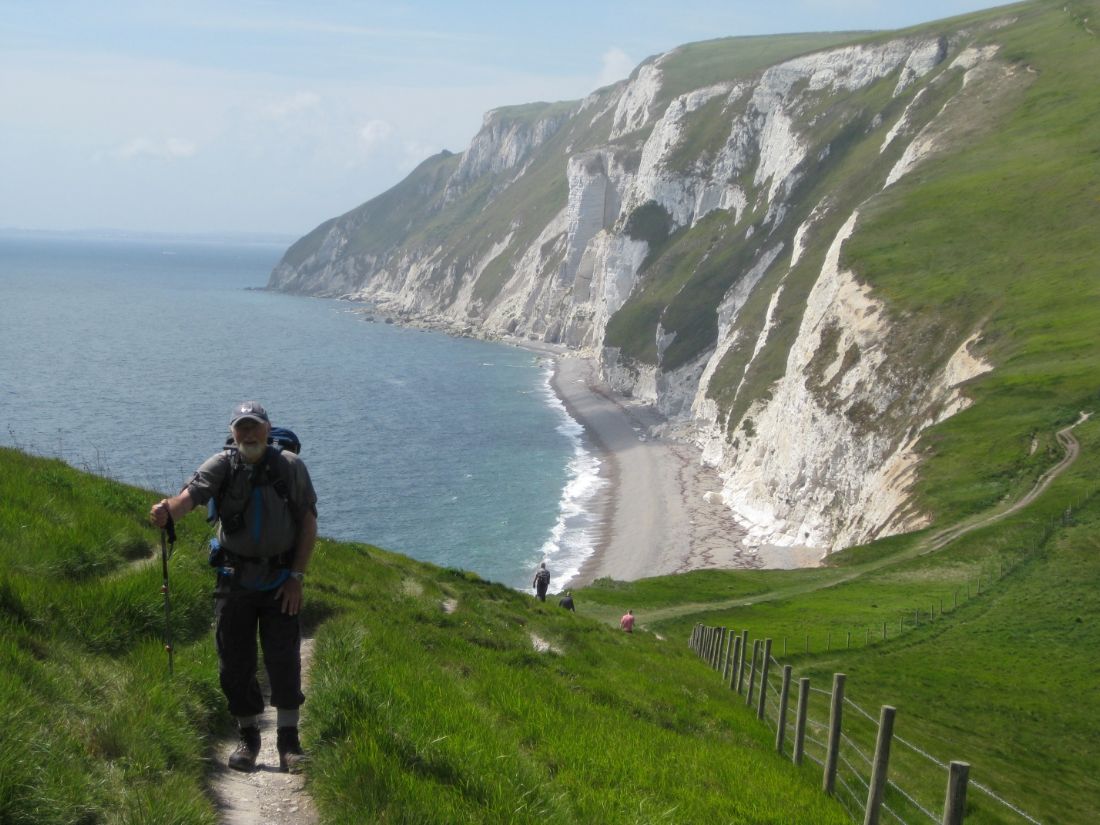 South West Coast Path hikers walk a cliffside trail above a pebble beach |  Peter Wells