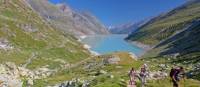 Group ascending a mountain on the Tour de Monte Rosa Walk above a stunning alpine lake | Andrew Bain