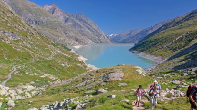 Group ascending a mountain on the Tour de Monte Rosa Walk above a stunning alpine lake | Andrew Bain