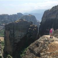 Hikers above a precipitous ridge overlooking Varlaam Monastery in Meteora | Kate Baker