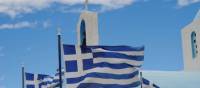 Greek flags flying above a white washed church in the Peloponnese