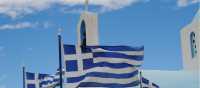 Greek flags flying above a white washed church in the Peloponnese
