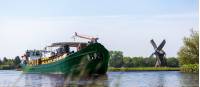 La Belle Fleur making its way along a canal in Holland with a windmill in the background