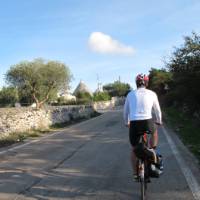 Cyclists approaching trulli houses near Alberobello, Puglia | Kate Baker