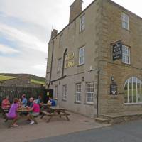 Drinkers outside Keld Lodge at the end of a day on the Coast to Coast | John Millen