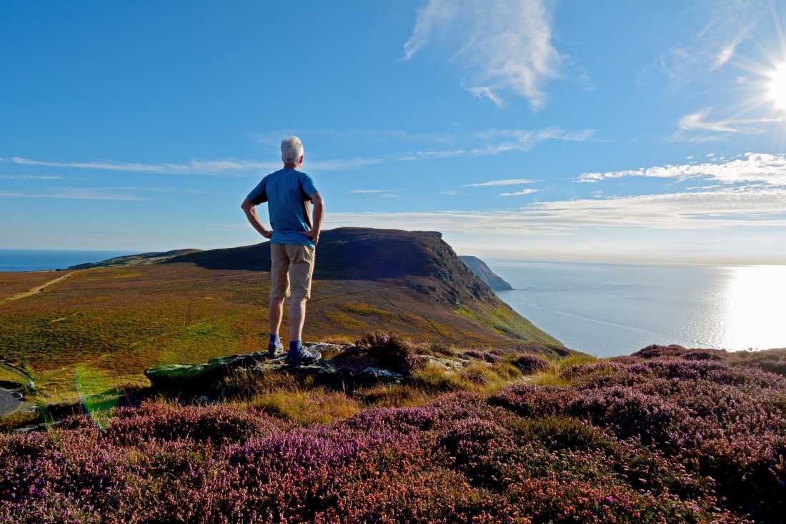 A walker enjoys a hilltop view on the Isle of Man