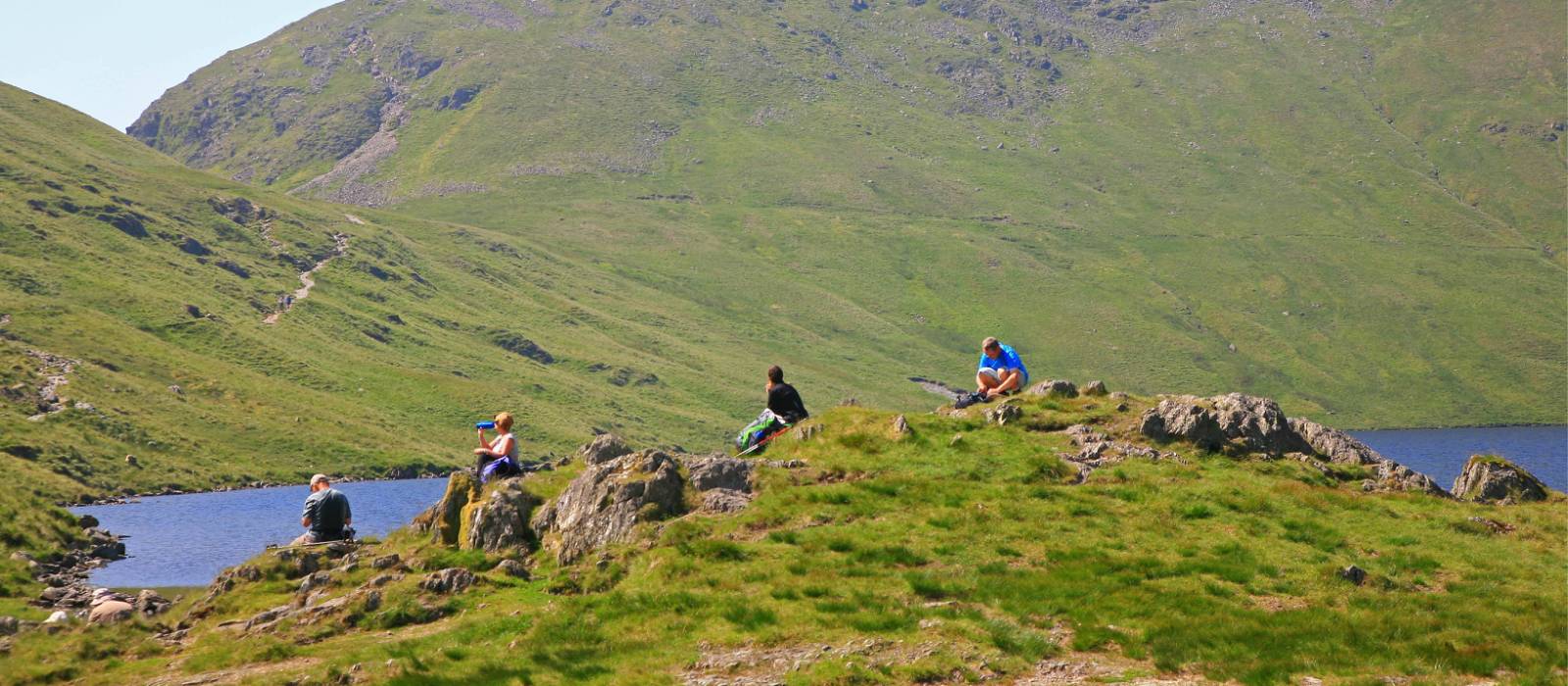 Walkers enjoy a break at Grisedale Tarn mountain lake | John Millen