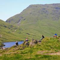 Walkers enjoy a break at Grisedale Tarn mountain lake | John Millen